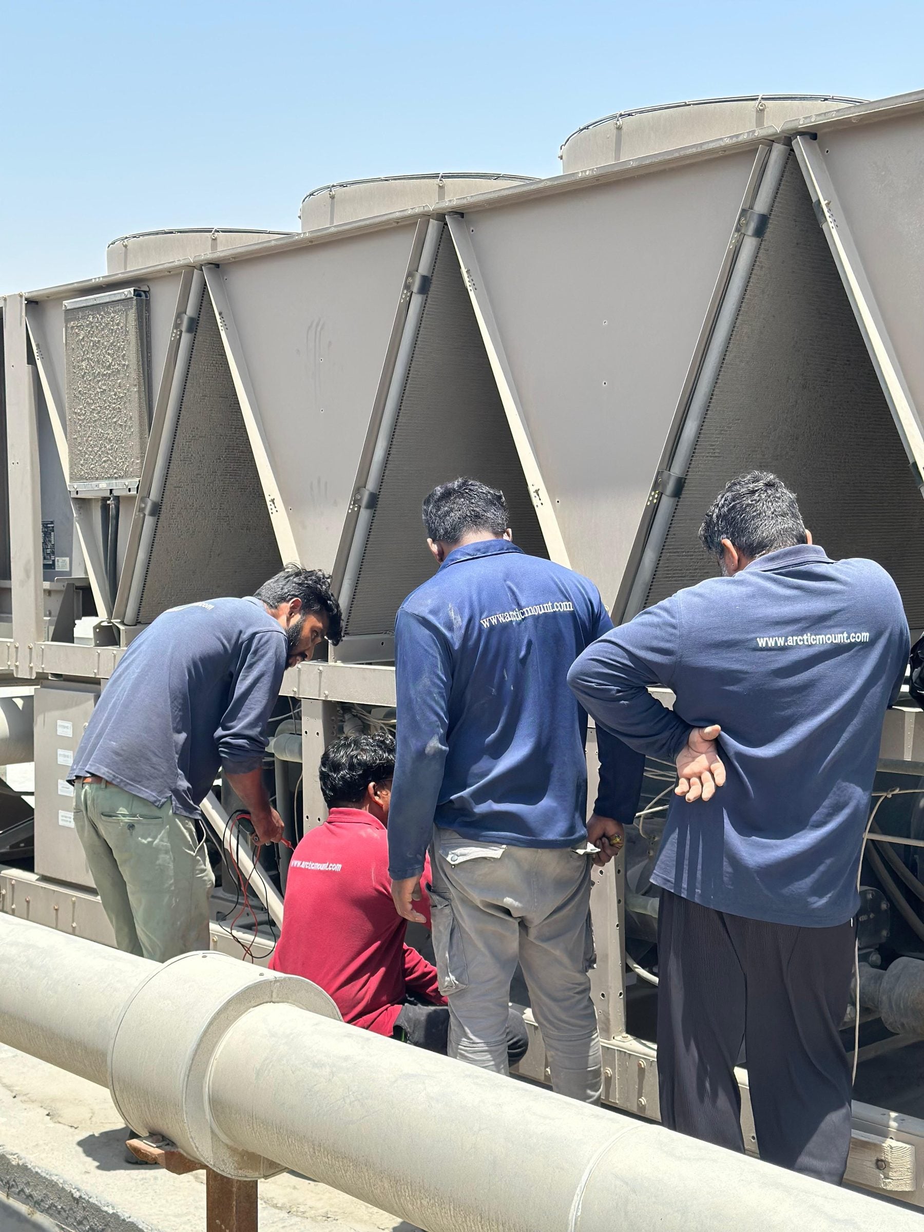Arctic Mount technicians in branded uniforms at a rooftop chiller
